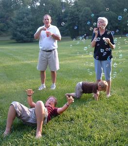 Ann Holler with husband Pete Holler, left, blows bubbles for two of her grandchildren, from left, Randy and Ryder Bentley, sons of Janet and Randall Bentley of Monroe, LA. She selected paintings depicting children because "they are an important part of my life now." 