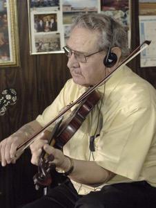 Gene Boyd, seen here playing his fiddle Thursday afternoon in the Star Barbershop, is closing next Thursday after clipping hair and playing hot bluegrass licks for 58 years in his State Street shop.(Photo by Andre Teague/Bristol Herald Courier)