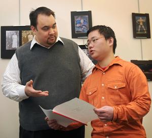 ETSU student Lin Lin Wei, right, discusses his essay with Scott Emmerine, president of AAF-NET.