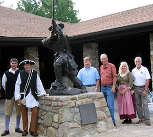 Posing at a statue of an Overmountain Man are, from left, Dustin Goforth, Mountain States Health Alliance Executive and cast member; U.S. Representative Phil Roe; Mike Carlton, Tennessee Department of Environment and Conservation Assistant Commissioner; Speaker of the House Kent Williams; Jennifer Bauer, manager of the Sycamore Shoals State Historic Area; and Herb Roberts, Tennessee State Parks, East Tennessee Manager.