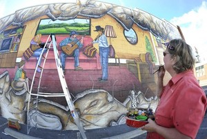 Artist Kathy Blair adds final touches to a mural outside Strings on West State Street. (Earl Neikirk|Bristol Herald Courier)