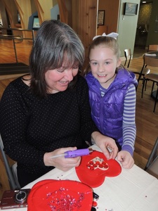 Mosaic artist Ruth Ann Kondylas works with 7-year-old Emily Perdue at "Art with a Heart."