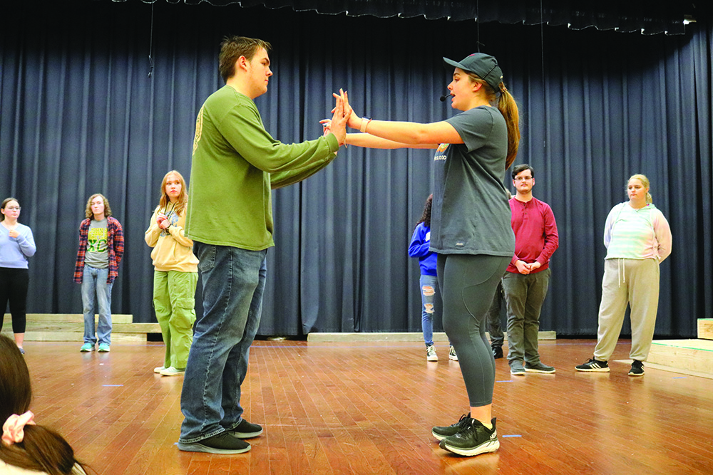 Shannon Dunning (right) teaches Owen Slaughter (left) the choreography.  Background (left to right)