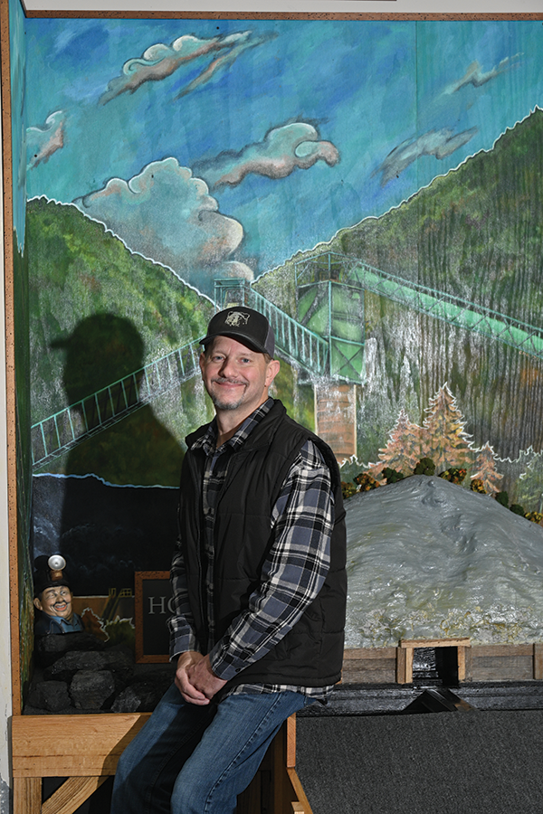 James Jarvis, owner of Traveling Bear Indoor Mini-Golf, poses with Hole #18, a tribute to coal miners.